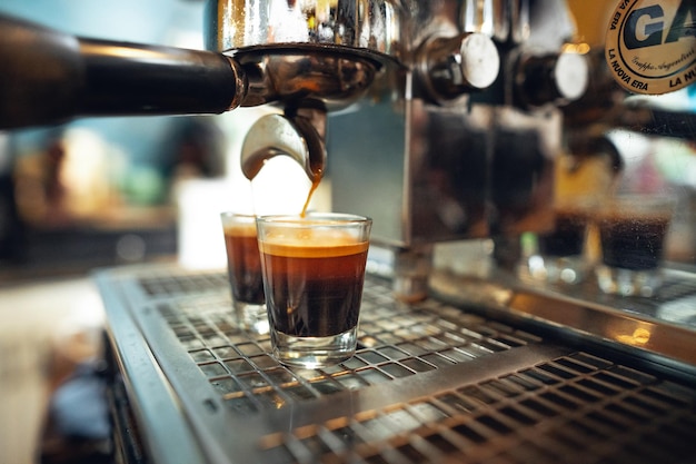 Espresso pouring into two glasses from a commercial espresso machine